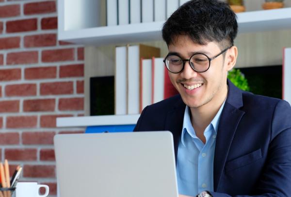 Young happy asian businessman working with laptop computer at office background