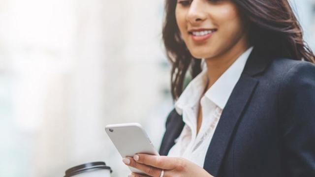 Woman on her phone and coffee in her hand