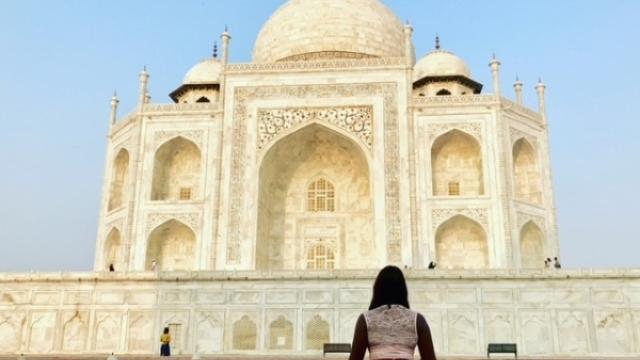 woman sitting on ground in front of landmark in india