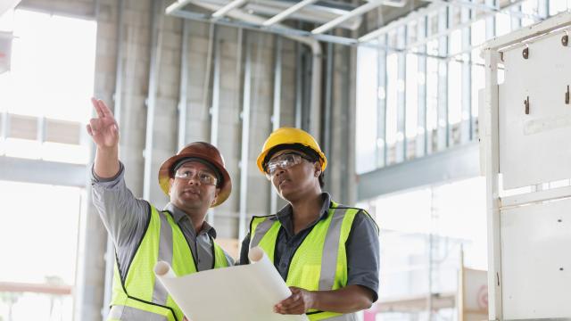 two construction workers pointing