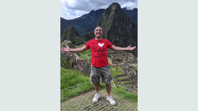 Man standing infront of Machu Picchu wearing an I love Taylor Swift red shirt