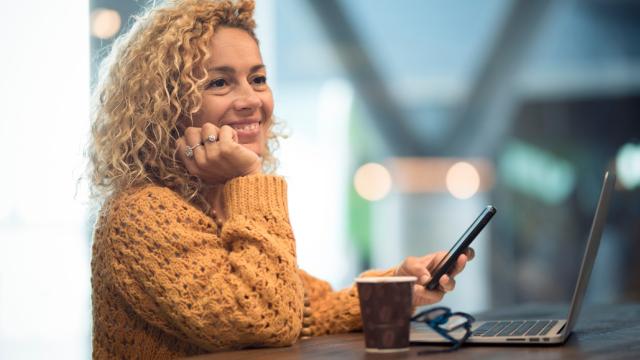 Cheerful happy people woman traveler wait at the airport gate for delay flight using modern technology device as phone and laptop computer