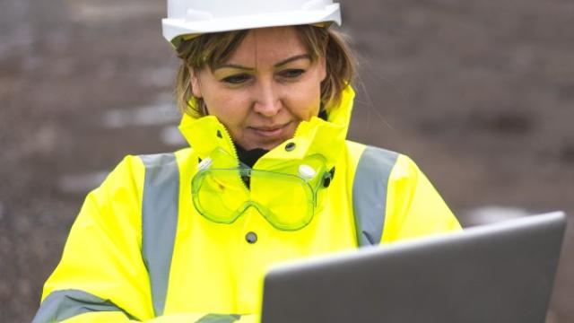 Woman in hard hat on laptop