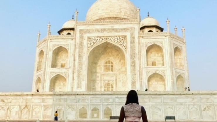 woman sitting on ground in front of landmark in india
