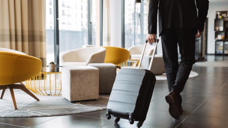 Man walking through hotel lobby with his wheelie suitcase