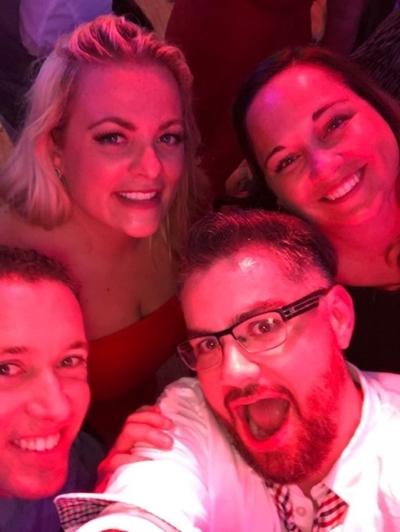 Group of friends taking a selfie at a party under red lighting