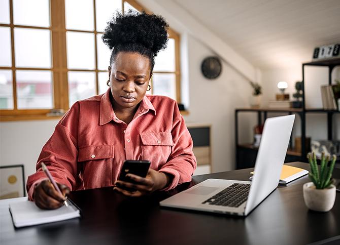 female executive analyzing her travel management company with her laptop open and cell phone in hand