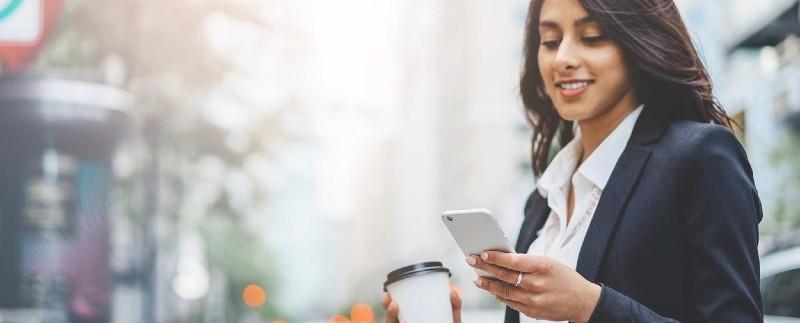 Woman on her phone and coffee in her hand