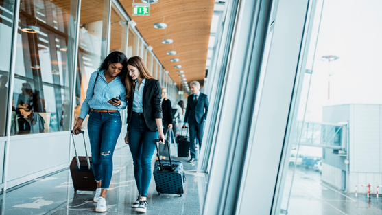 Two girls boarding a plane looking at a phone