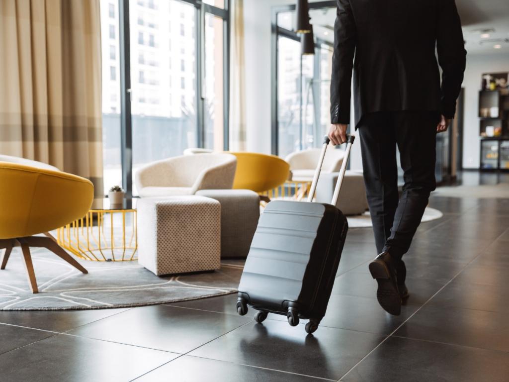 Man walking through hotel lobby with his wheelie suitcase
