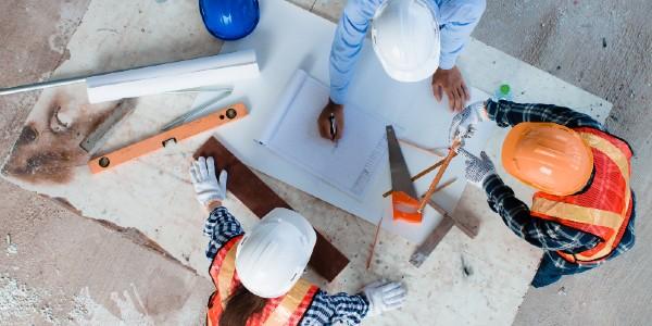 Team of young man and woman engineer and architects working, meeting, discussing,designing, planing, measuring layout of building blueprints in construction site floor at factory