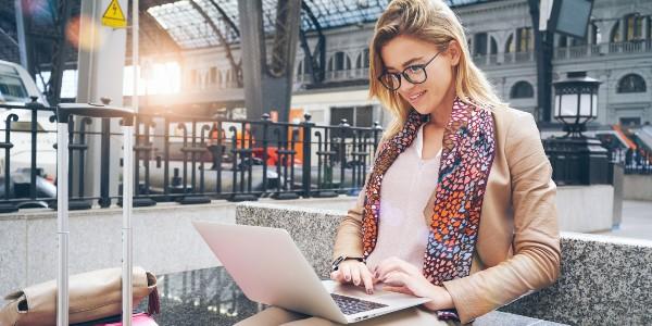 Caucasian woman using net-book while sitting in train station interior. modern businesswoman using a laptop computer while waiting for the train.