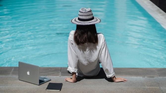 business traveller sitting poolside with laptop
