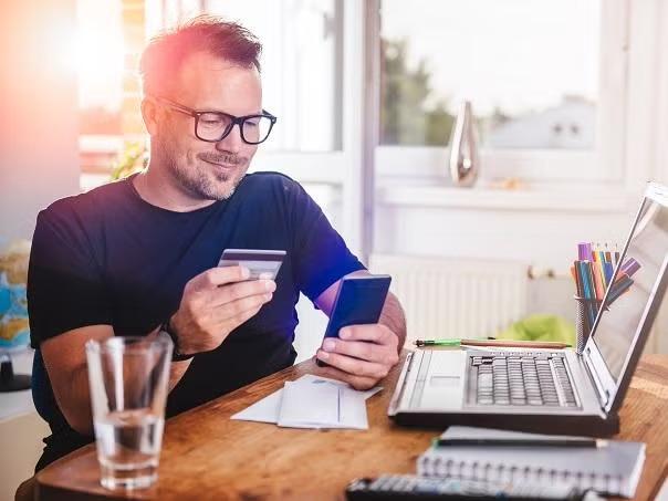 Man holding credit card and smartphone demonstrating the importance of understanding credit card insurance.