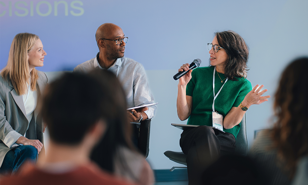 Three speakers engage in a panel discussion, sharing ideas with the audience.