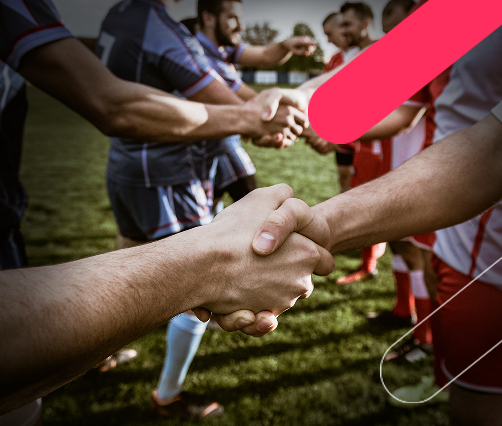 Photograph of two rugby players shaking hands on grassy field before match