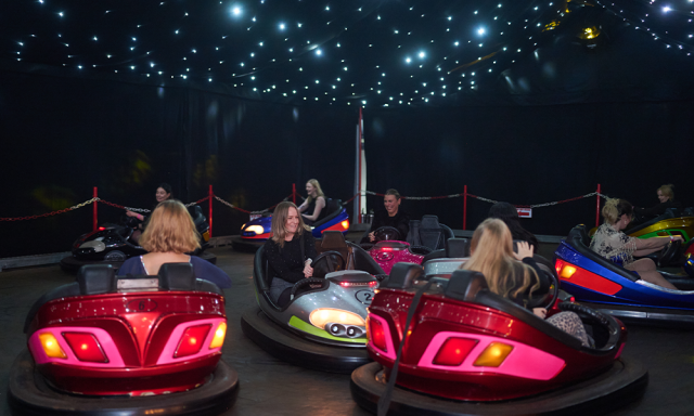 Group of people enjoying bumper cars under a starry night sky.