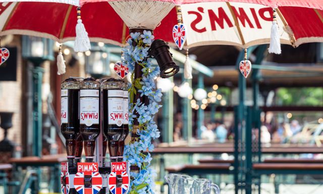 Bar counter adorned with an umbrella and decorative flowers, with bottles displayed behind.