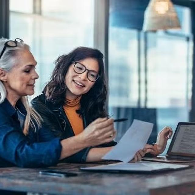 Two women sitting in an office in discussion demonstrating the importance of choosing the best insurance with a travel expert.